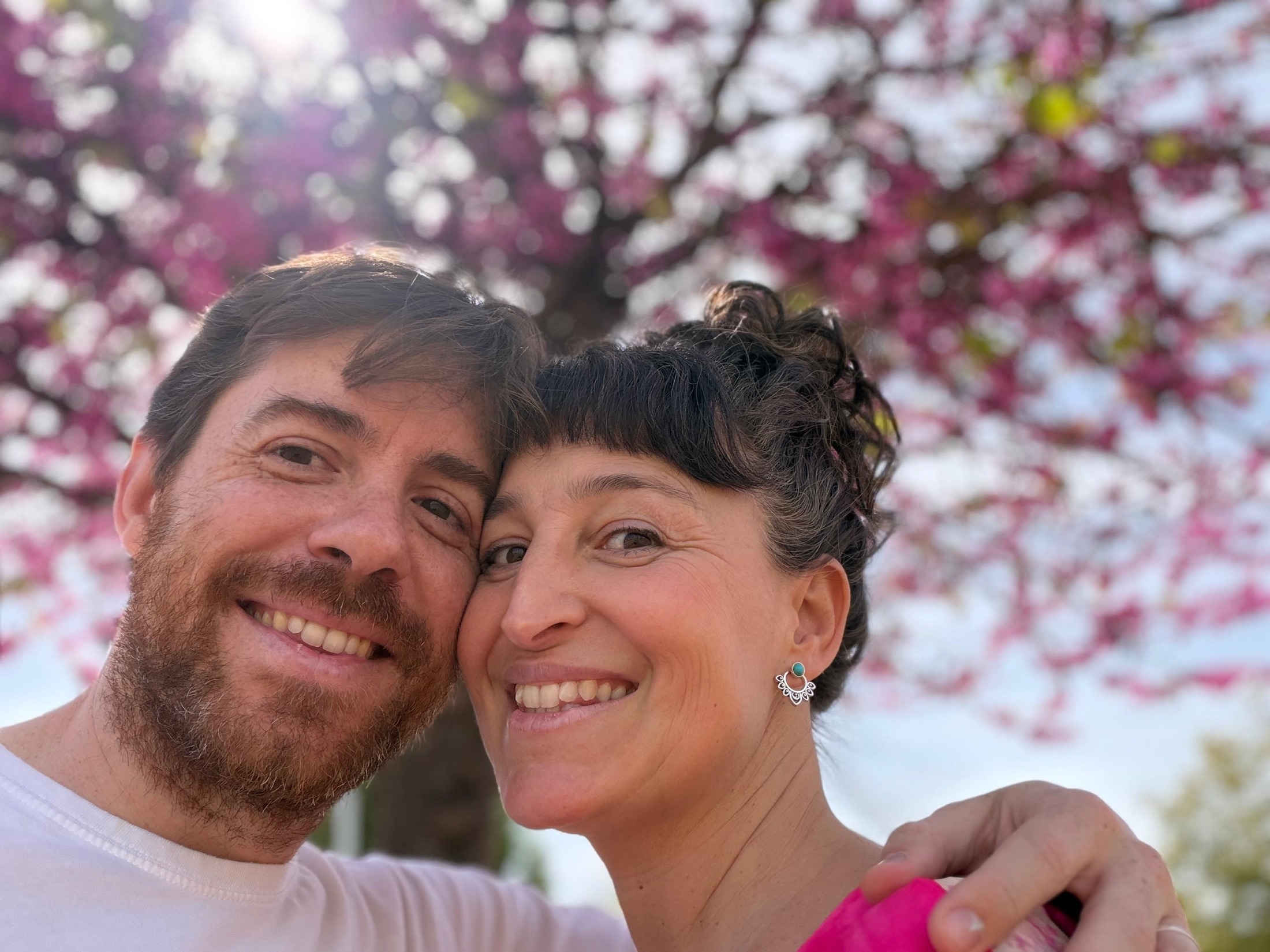 Verónica y Daniel sonriendo bajo un árbol en flor